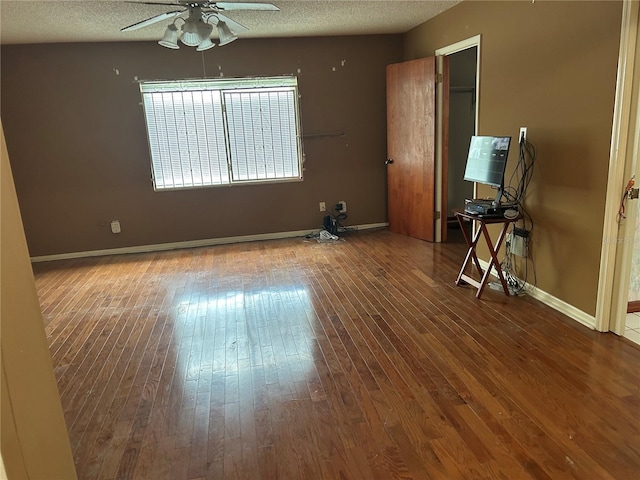 unfurnished room featuring baseboards, ceiling fan, hardwood / wood-style flooring, and a textured ceiling