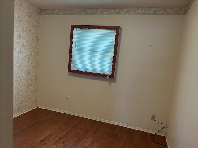 spare room with baseboards, wood finished floors, and wallpapered walls