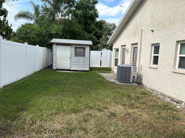 view of yard featuring a fenced backyard, an outbuilding, central AC, and a shed