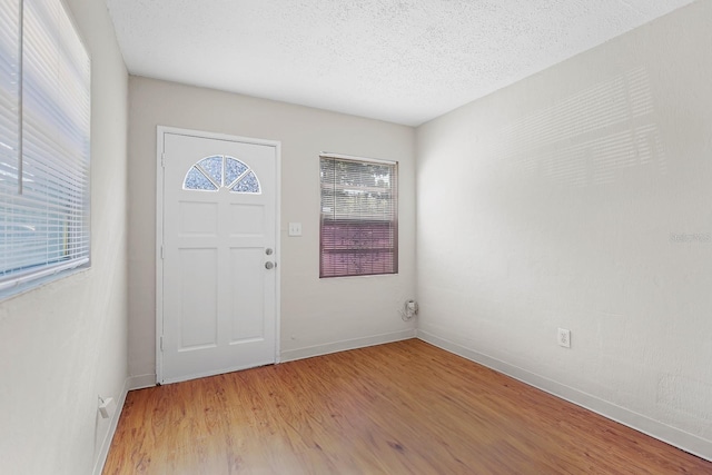 entryway featuring light wood-style floors, a textured ceiling, and baseboards