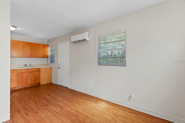 kitchen featuring light wood-type flooring, a sink, a wall unit AC, and light countertops