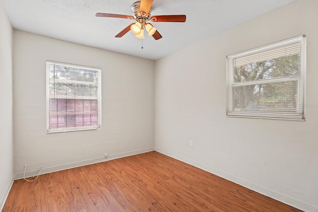 empty room with a healthy amount of sunlight, baseboards, ceiling fan, and wood finished floors