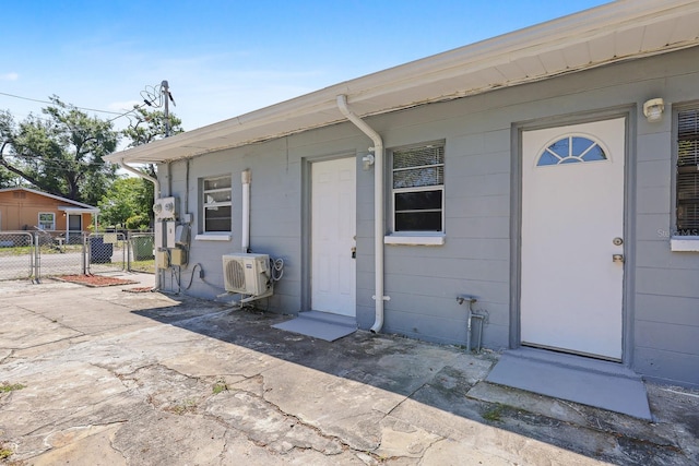 doorway to property with fence, ac unit, and concrete block siding