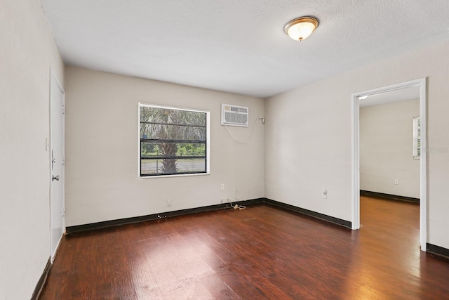 spare room featuring baseboards, a wall mounted air conditioner, and wood finished floors