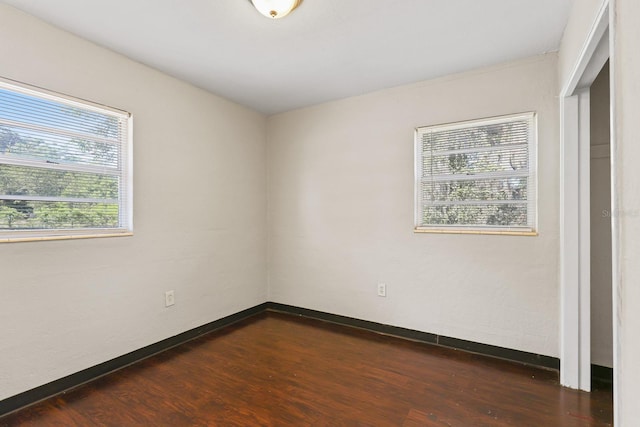 spare room featuring baseboards and dark wood-style floors