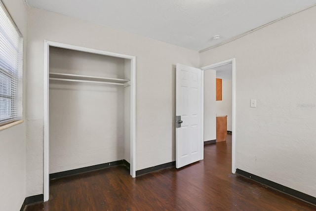 unfurnished bedroom featuring baseboards, a closet, and wood finished floors
