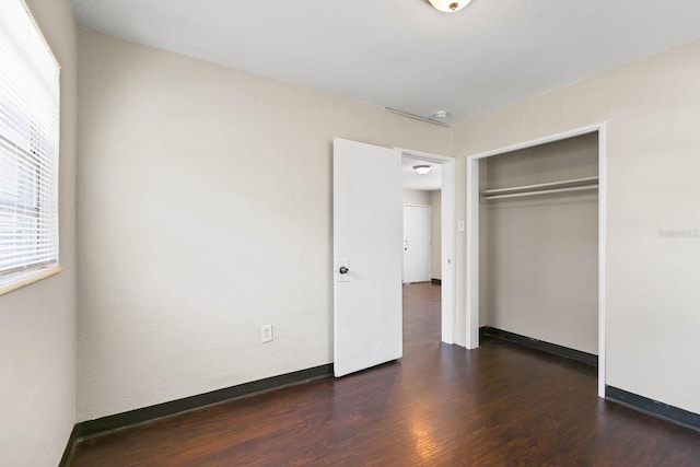 unfurnished bedroom with multiple windows, a closet, and wood finished floors