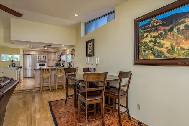 2202 Donato Dr, Belleair Beach, FL 33786 - dining room featuring a raised ceiling, recessed lighting, and light wood-style flooring