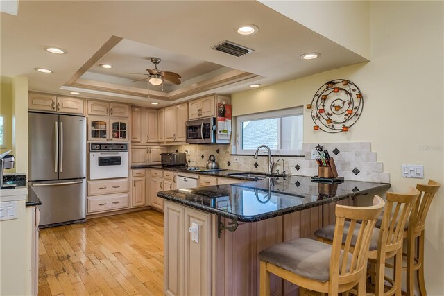 2202 Donato Dr, Belleair Beach, FL 33786 - kitchen featuring appliances with stainless steel finishes, a sink, light wood finished floors, a peninsula, and visible vents
