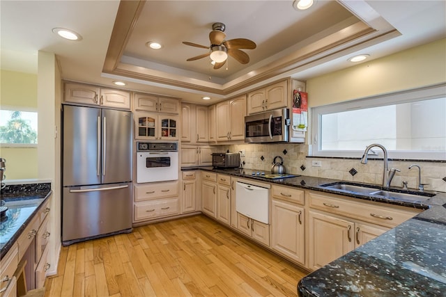 2202 Donato Dr, Belleair Beach, FL 33786 - kitchen with decorative backsplash, a raised ceiling, a sink, light wood-style flooring, and stainless steel appliances