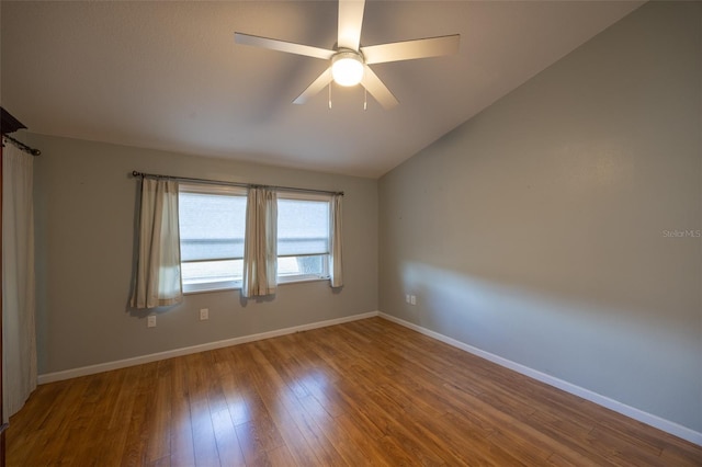 empty room with baseboards, ceiling fan, wood finished floors, and vaulted ceiling