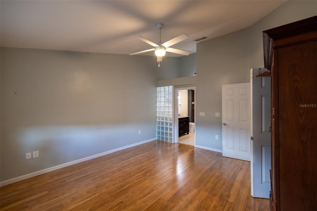 unfurnished room featuring visible vents, a towering ceiling, wood finished floors, baseboards, and a ceiling fan