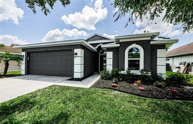 prairie-style home with a garage, stucco siding, concrete driveway, and a front lawn