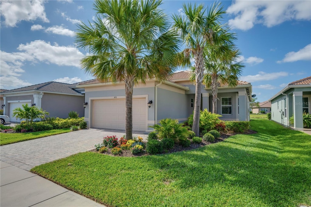 view of front facade with decorative driveway, an attached garage, a front lawn, and stucco siding