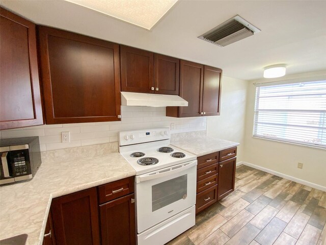 3311 Teeside Dr, New Port Richey, FL 34655 - kitchen featuring white electric range oven, stainless steel microwave, under cabinet range hood, light countertops, and backsplash