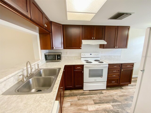 3311 Teeside Dr, New Port Richey, FL 34655 - kitchen with white appliances, under cabinet range hood, light countertops, and backsplash