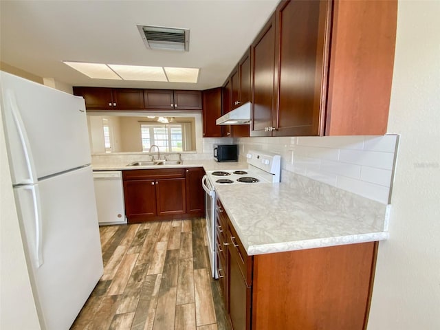 3311 Teeside Dr, New Port Richey, FL 34655 - kitchen featuring white appliances, under cabinet range hood, light wood-style flooring, tasteful backsplash, and light countertops