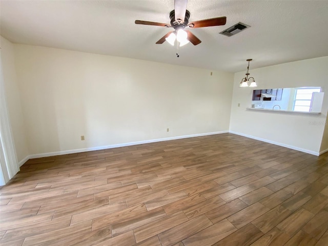 3311 Teeside Dr, New Port Richey, FL 34655 - empty room featuring wood finished floors, a ceiling fan, and a chandelier