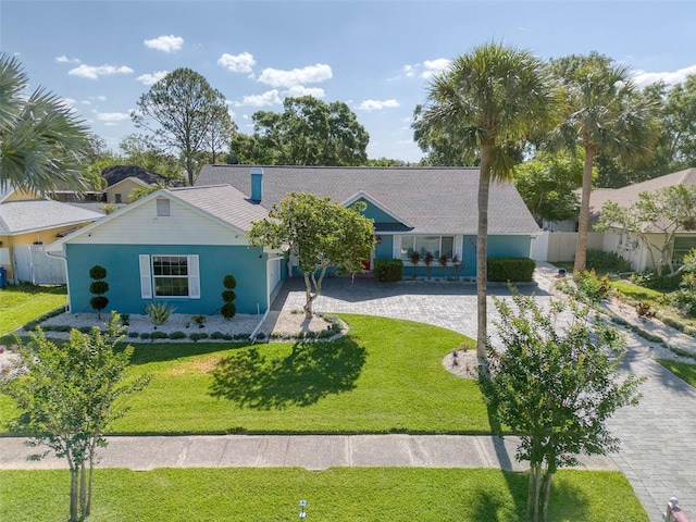ranch-style home featuring a front lawn, stucco siding, and fence