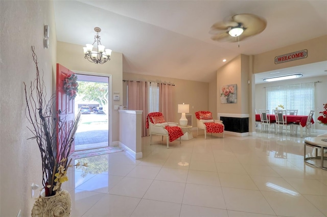 tiled foyer entrance with baseboards, lofted ceiling, a chandelier, and a fireplace
