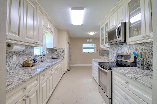 kitchen with a sink, baseboards, tasteful backsplash, and stainless steel appliances