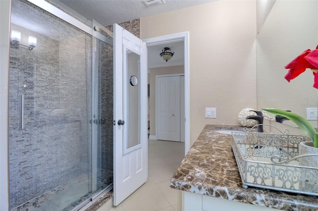 bathroom with double vanity, visible vents, tile patterned flooring, a shower stall, and a sink