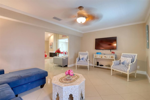 living room featuring tile patterned flooring, a ceiling fan, baseboards, visible vents, and ornamental molding