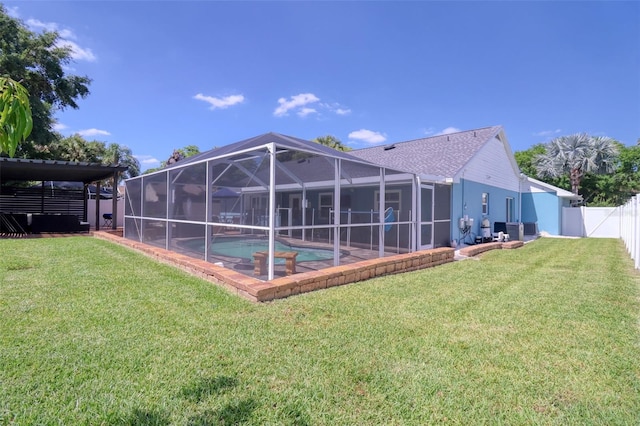 back of house with a lawn, a fenced backyard, an outdoor pool, and a lanai