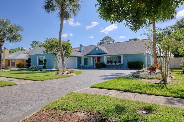 ranch-style home featuring a garage, decorative driveway, and a front yard