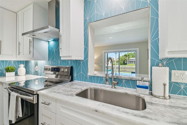 kitchen with backsplash, stainless steel range with electric cooktop, a sink, and wall chimney exhaust hood
