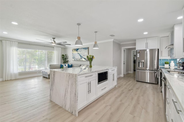 kitchen with crown molding, a center island, built in microwave, stainless steel fridge with ice dispenser, and baseboards