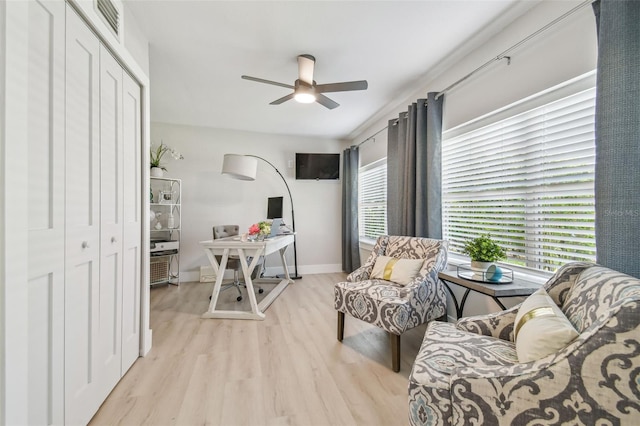 living area with baseboards, a ceiling fan, light wood-type flooring, and visible vents