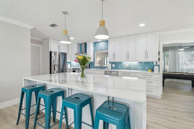 3922 Fontainebleau Dr, Tampa, FL 33634 - kitchen with appliances with stainless steel finishes, wall chimney range hood, crown molding, white cabinets, and tasteful backsplash