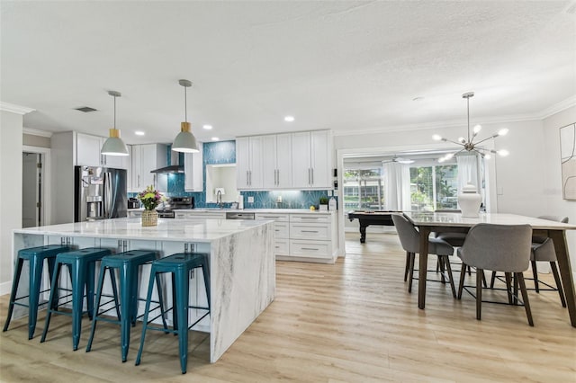 3922 Fontainebleau Dr, Tampa, FL 33634 - kitchen with stainless steel appliances, ornamental molding, a large island, wall chimney range hood, and a sink