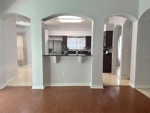 2820 Pankaw Ln, Valrico, FL 33596 - kitchen with stainless steel refrigerator with ice dispenser, dark countertops, light wood finished floors, tasteful backsplash, and baseboards