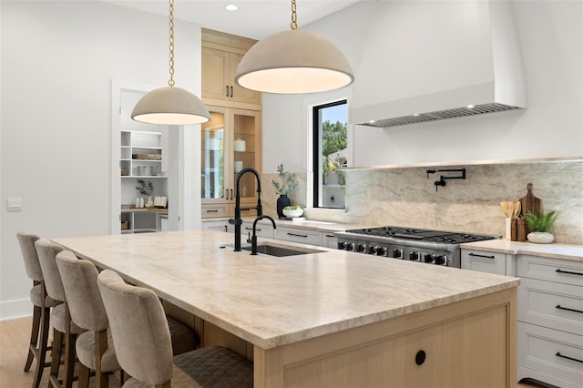 2218 S Occident St, Tampa, FL 33629 - kitchen with a kitchen island with sink, backsplash, light stone countertops, a sink, and custom range hood