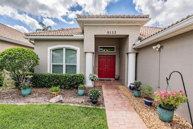 view of exterior entry featuring a tiled roof and stucco siding