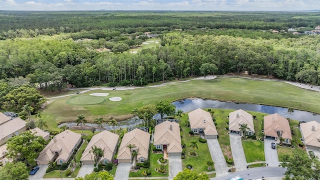 drone / aerial view with a water view, view of golf course, and a wooded view