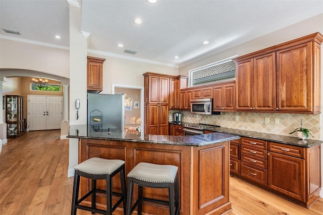 kitchen featuring visible vents, arched walkways, tasteful backsplash, ornamental molding, and stainless steel appliances