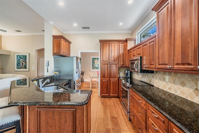 kitchen featuring visible vents, light wood-style floors, a kitchen bar, a sink, and appliances with stainless steel finishes