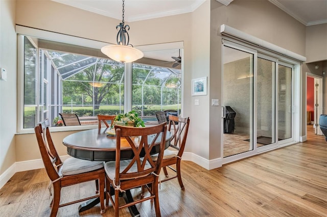dining room with ornamental molding, wood finished floors, baseboards, a sunroom, and a ceiling fan