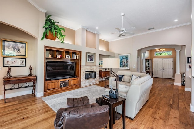 living room with arched walkways, baseboards, visible vents, and ornamental molding
