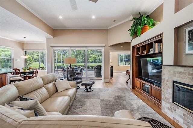 living room featuring crown molding, plenty of natural light, a ceiling fan, and light wood-type flooring
