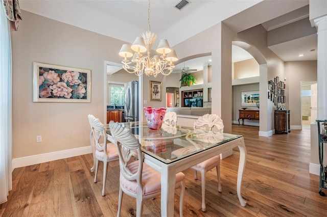 dining room featuring visible vents, arched walkways, light wood finished floors, and a chandelier