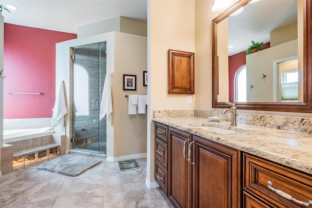 bathroom featuring vanity, baseboards, a garden tub, and a shower stall