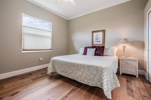 bedroom with baseboards, ornamental molding, and wood finished floors