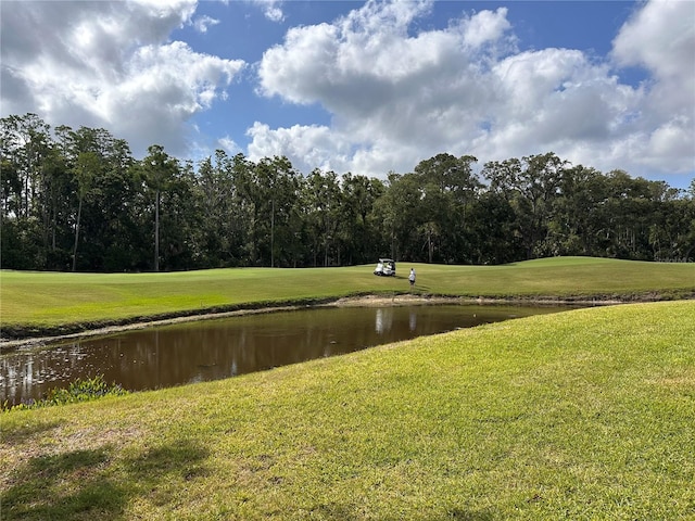 view of community featuring view of golf course, a water view, and a yard