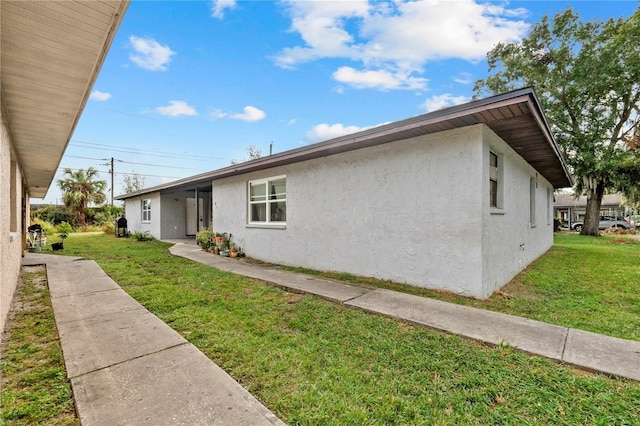 view of side of property with stucco siding and a yard