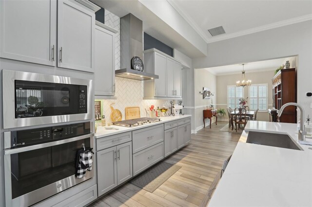 21746 Amelia Rose Way, Land O Lakes, FL 34637 - kitchen with visible vents, a sink, ornamental molding, stainless steel appliances, and wall chimney exhaust hood