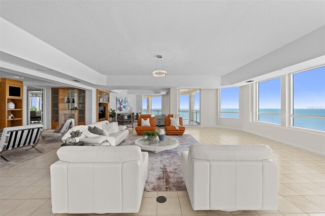 1170 Gulf Blvd Unit 2101, Clearwater Beach, FL 33767 - living area with light tile patterned flooring, a textured ceiling, a water view, and built in shelves